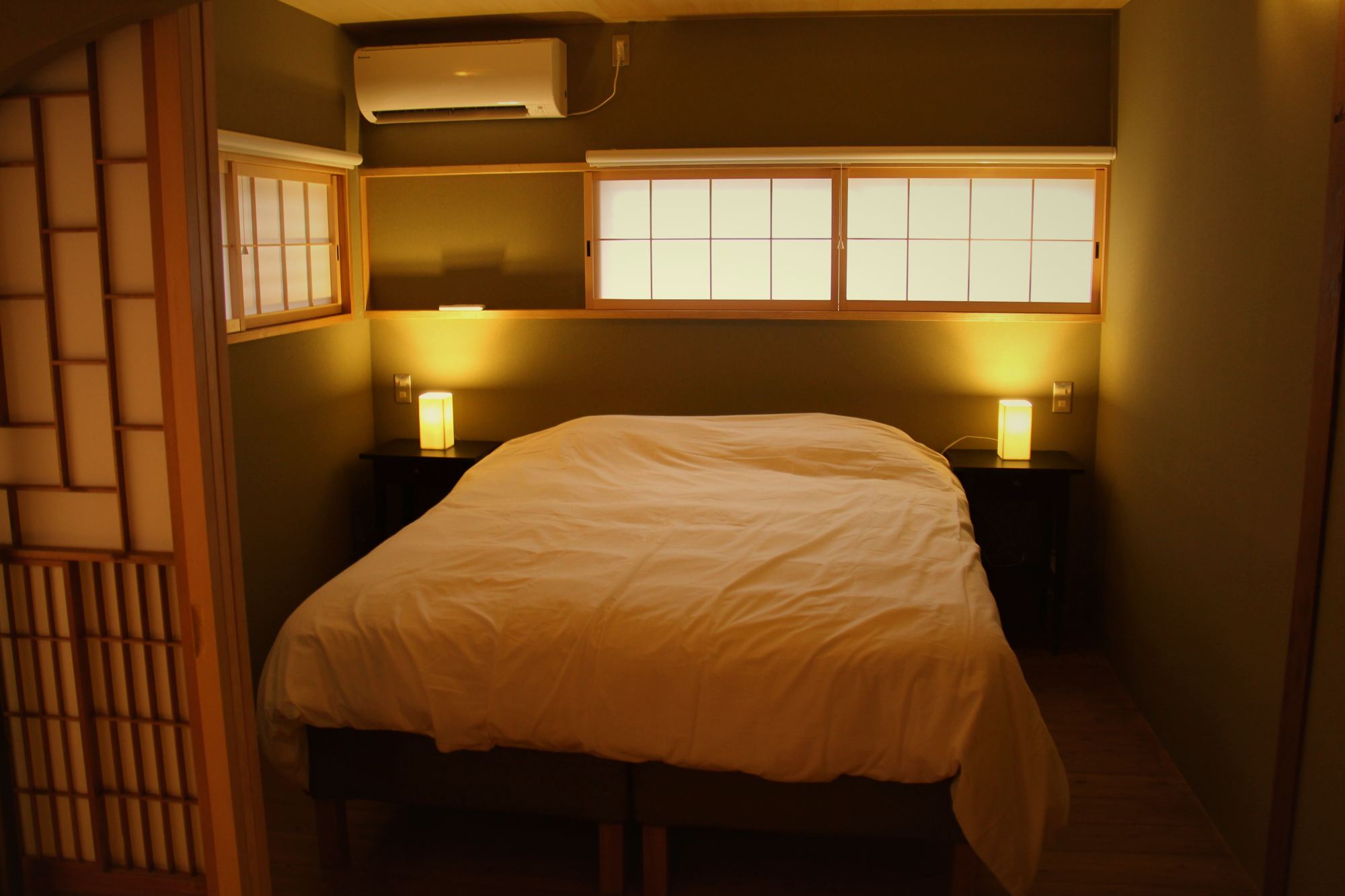 Double bedroom with warm bedside lights and shoji windows at Enso-an