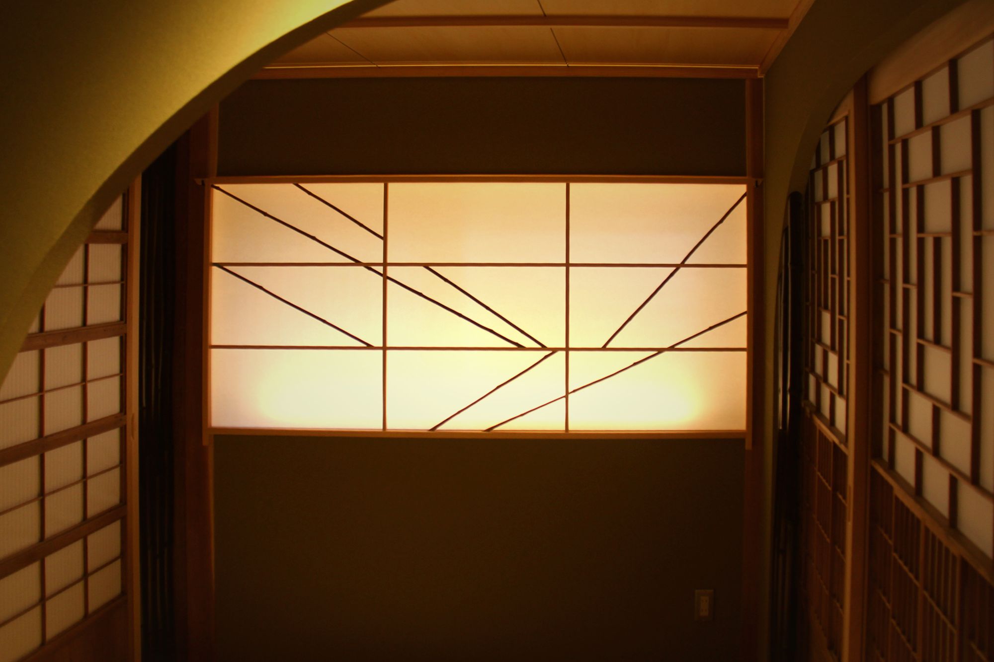 Glowing shoji screen framed by an arched opening inside Enso-an, Kyoto