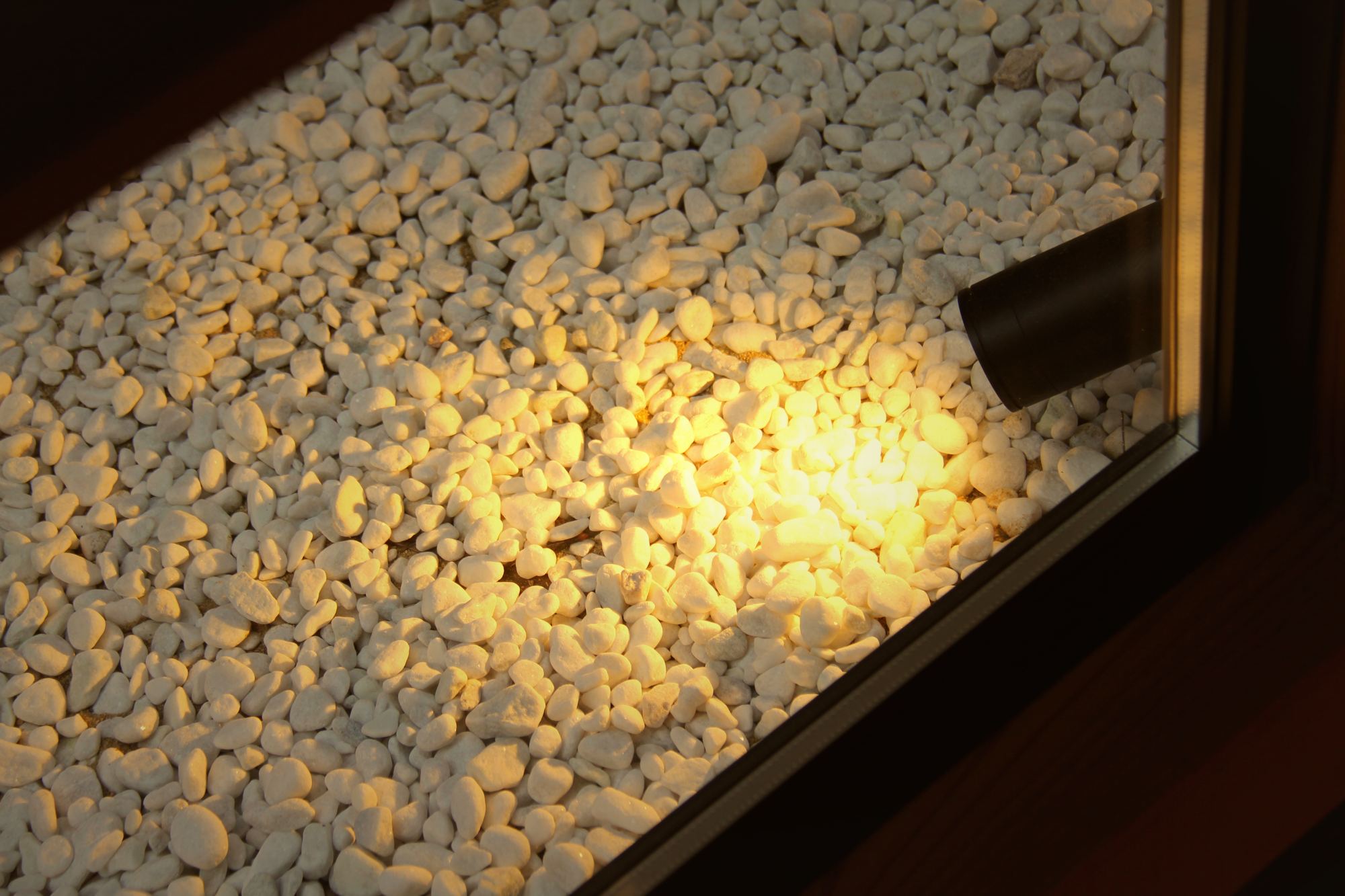 Lit white-pebble stone garden seen through the entrance window of Enso-an